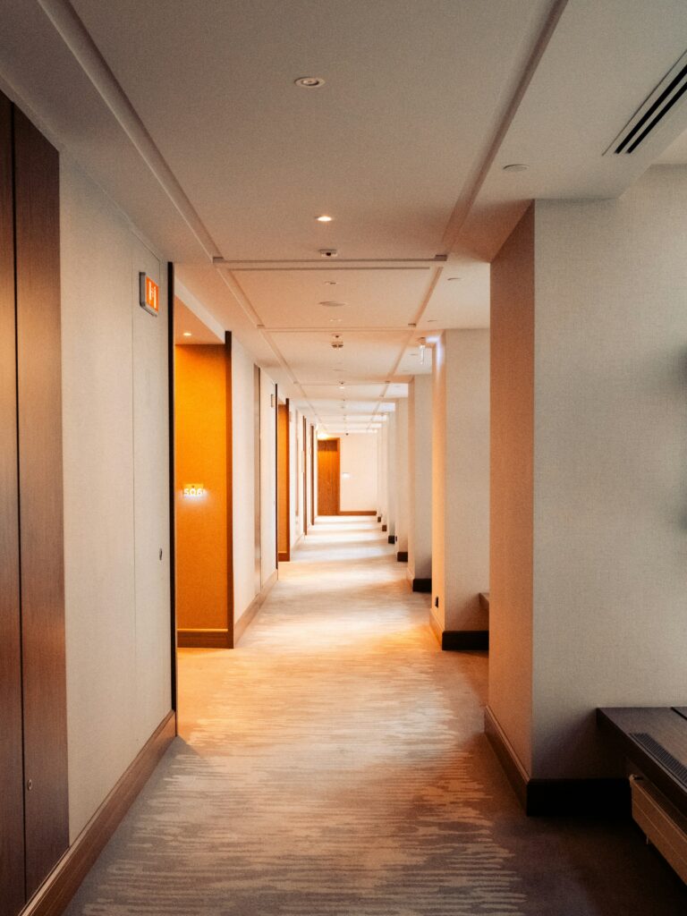 Warm, softly lit hotel corridor with carpeted floor (contextual image)